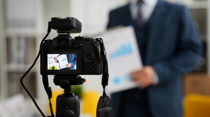 Male in suit and tie show stats graph pad making promo videoblog or photo session in office camcorder to tripod closeup. Vlogger selfie sale solution or finance advisor management information