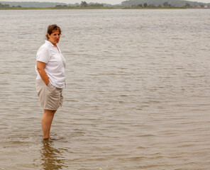 A woman stands in the water, looking out at the horizon