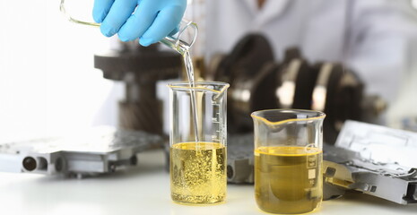 Male hands in protective gloves hold test tube in hands produces chemistry test of motor oil...