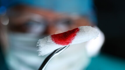 Surgeon in sterile uniform arms holding and passing to colleague tools with bio material wad closeup while operating patient. Stop bleeding put stitch er 911 concept