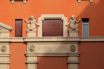 Piazza dei Sanniti Square Building Facade Detail with Sculpted Figures and Latin Inscription in Rome, Italy