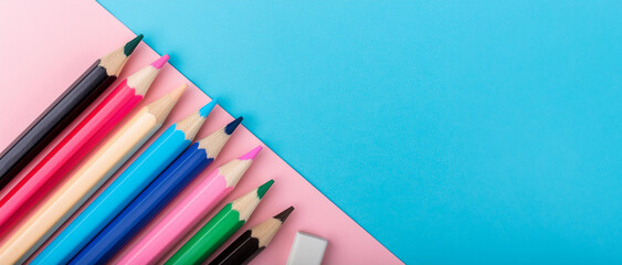colorful sharp pencils and an eraser over a modern split blue and pink background. creativity, fun, idea generation and back to school concepts  
