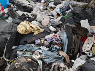 Close-up of pile of discarded clothes and other waste dumped at side of street in the West Midlands