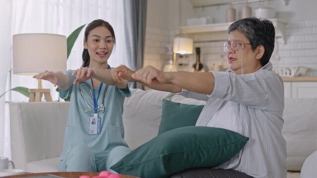 Asian Elderly woman holding a dambell used for rehabilitation in home,doing arm and hand physiotherapy for elderly woman, to Physical therapy,treat myasthenia gravis,to nursing home concept