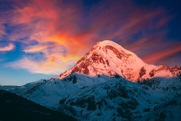 Stepantsminda, Gergeti, Georgia. Mount Kazbek Covered Snow In Winter Sunrise. Morning Dawn Colored...