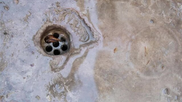 Grifo con pérdida goteando. Gotas de agua caen en la superficie de la pileta, estallan en el piso salpicando y formando ondas circulares abstractas.