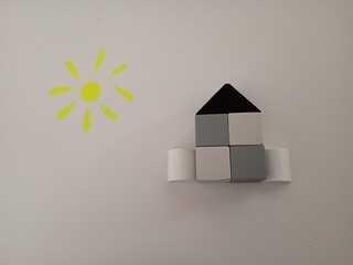 house made of wooden gray cubes with sun on a white background