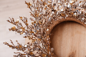 Fototapeta premium A handmade wreath with golden leaves and dried flowers on a wooden base.