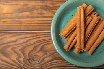 Cinnamon sticks on a textured wooden background. Cinnamon roll. Spicy spice for baking, desserts and drinks. Fragrant ground cinnamon. cinnamon powder Close-up. Place for text. copy space