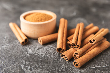 Cinnamon sticks on a textured wooden background. Cinnamon roll. Spicy spice for baking, desserts and drinks. Fragrant ground cinnamon. cinnamon powder Close-up. Place for text. copy space