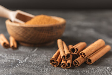 Cinnamon sticks on a textured wooden background. Cinnamon roll. Spicy spice for baking, desserts and drinks. Fragrant ground cinnamon. cinnamon powder Close-up. Place for text. copy space