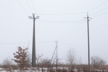 Field covered with snow. Electric poles. Foggy morning.