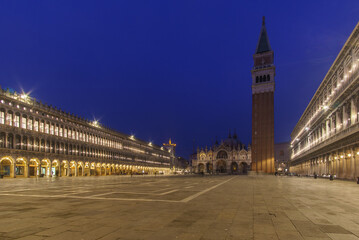 An empty illuminated San Marco square with the bell tower and the cathedral at blue hour on a...