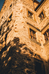 Exterior of Czocha castle in Poland. Old stone walls and tall windows covered with sunset sunlight. - 778299978