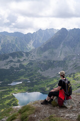 A woman rests after herding on a mountain looking at the High Tatras valley. Sunny summer day with...