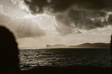 Sunlight piercing through dark dramatic clouds over the sea in Sardinia, Italy