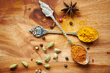 Spoons, spice and selection of seasoning for health on kitchen table, turmeric and cardamom for...