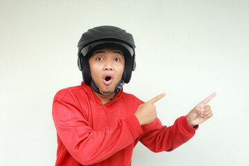 Young Asian man wow expression and pointing while wearing a motorcycle helmet. Safety concept.