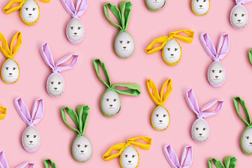 Handmade Easter eggs with colored Bunny Ears on Pink Background, minimal Flat lay pattern, Easter holiday concept. Creative Spring festive layout. Top view Diy decorated wooden eggs, pastel colors
