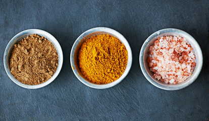 Top view, spices in bowl and ingredients for food, culinary and flavor with powder or ground seasoning for cooking background. Sea salt, cinnamon and turmeric for meal and cuisine with catering