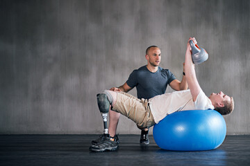 Trainer, person with a disability and prosthetic leg and dumbbell in physiotherapy, studio and gym...
