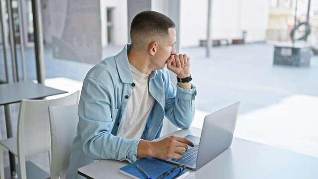 Focused man using laptop in a brightly lit modern library, depicting education and technology.