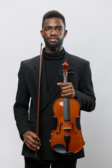 Elegant African American man in black suit holding violin on white background for classical music concept © SHOTPRIME STUDIO