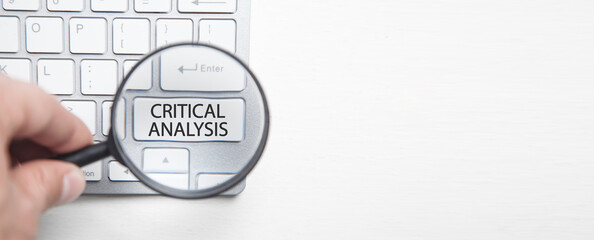 Male hand showing magnifying glass with a Critical Analysis text.