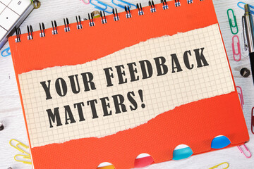 Your Feedback Matters written on a piece of paper in a cage on the background of an orange notebook...