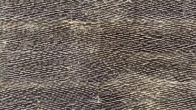 4K video. Close up waterfall motion footage on natural andesite stone rough cladding wall texture. Water dropping flowing down on black honed andesite stone.
