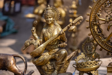 A handmade brass idol of Goddess Saraswati is a stunning piece of art that blends craftsmanship with spiritual significance. - obrazy, fototapety, plakaty