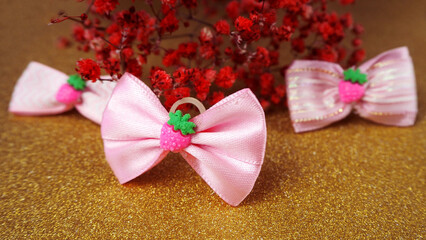 three small pink dog bows stand on a gold glitter background with red dried flowers. accessories for long hair. for pets. bows for dogs