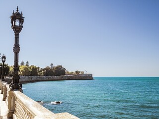 City walls with the bastion Baluarte de la Candelaria and the park of Alameda Apodaca in the Old Town of Cadiz, Spain - obrazy, fototapety, plakaty