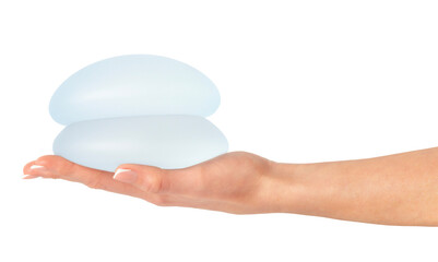 Female holding breast implants on hand, isolated