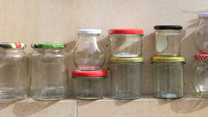 Empty glass jars line and stapled against wall