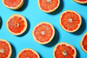 Fresh grapefruits on vibrant blue background arranged in a top view flat lay style, perfect for healthy food concept
