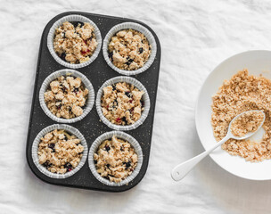 Making muffins with black currant and sugar oatmeal crumble on a light background, top view