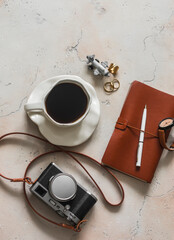 Travel mood - a cup of coffee, a retro-style camera, a notebook on a marble table in a cafe, top view