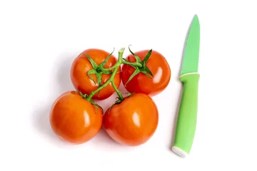 Foto op Aluminium A bunch of fresh ripe red greenhouse tomatoes on the vine with a green paring knife isolated on white © SockaGPhoto