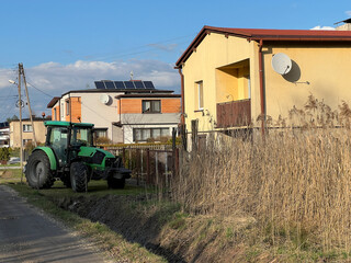 A tractor parked in front of the house, just like a car - 778350747