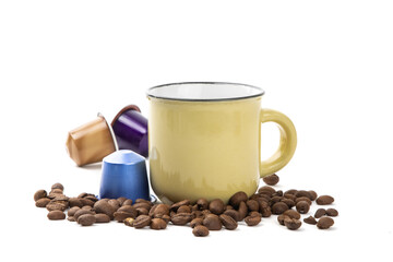 A yellow cappuccino cup surrounded by a coffee beans and colorful espresso coffee maker pods isolated on white