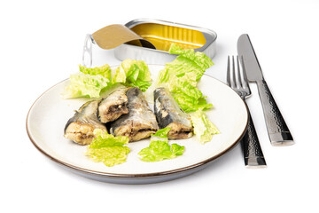 A plate of tinned sardines garnished with pieces of lettuce with a knife and fork isolated on white
