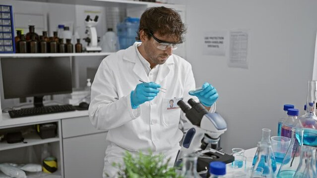 Handsome bearded scientist analyzing plant samples in a modern laboratory setting, equipped with microscope and chemicals.
