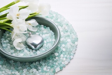 White orchids and silver heart on green pebbles in bowl, on white background, still life photography, interior design, minimalist