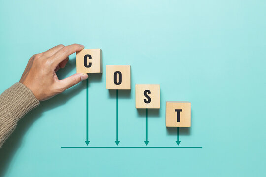 Concept of cost, lean or cost reduction. Hand placing a wooden block with the word cost and down arrow for decreasing expense to maximize profits