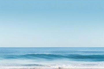 Obraz premium Minimalist beach photography of a blue ocean wave with a clear blue sky and white sand