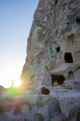 Sun flare peeking through ancient cave dwellings in Cappadocia, showcasing a blend of history and...