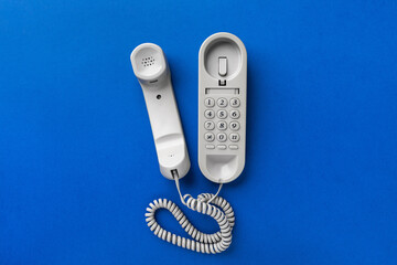 Old corded telephone on a blue background, top view