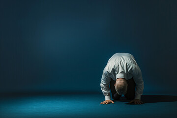 A man kneeling on the floor with his hands clasped in front of him - obrazy, fototapety, plakaty