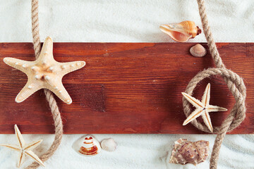Fototapeta na wymiar Seashells, starfish, rope and wooden board on the sand.